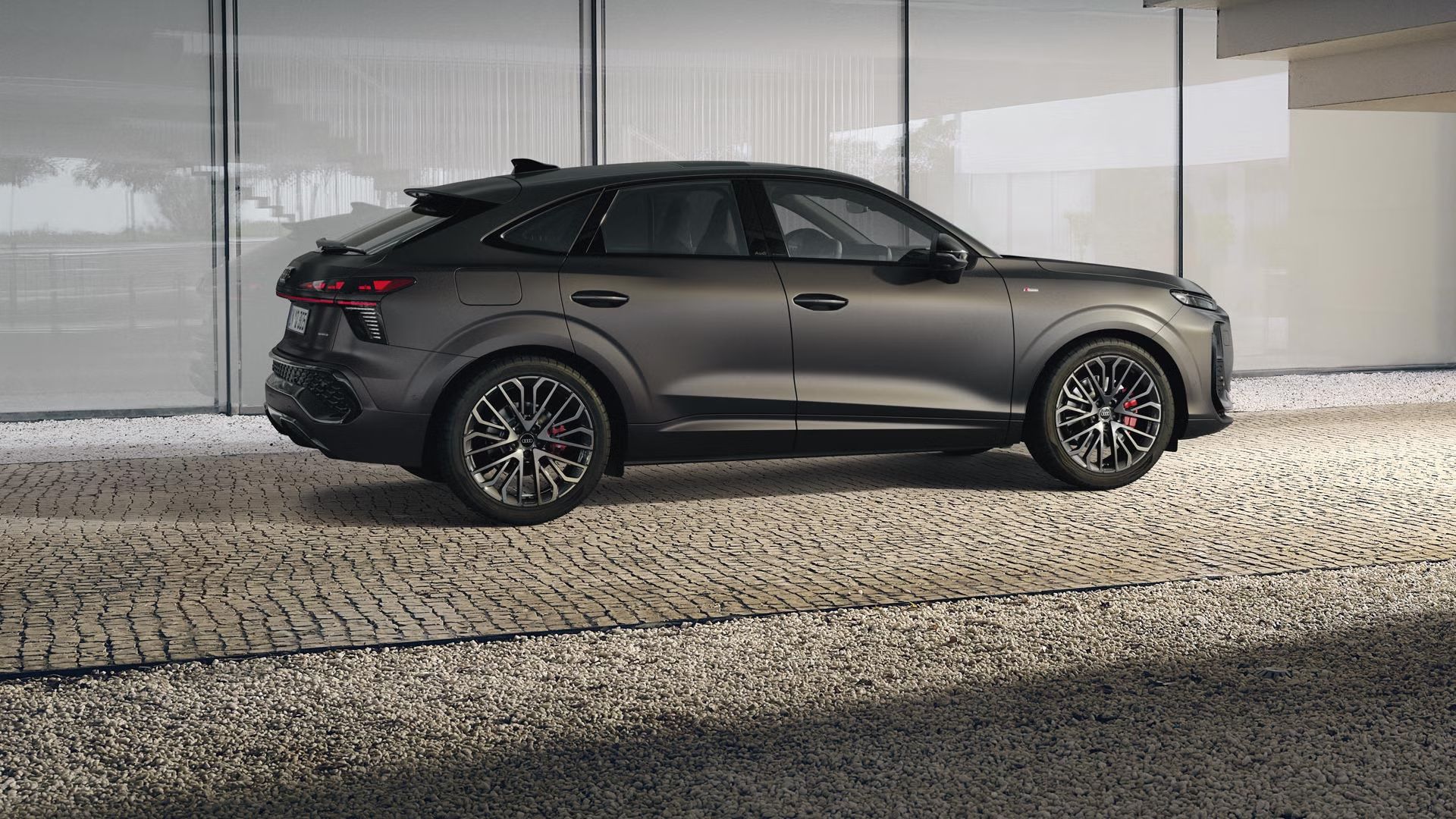 Der Q3 Sportback parkt vor dem Treppengeländer eines Gebäudes auf einem gepflasterten Weg.