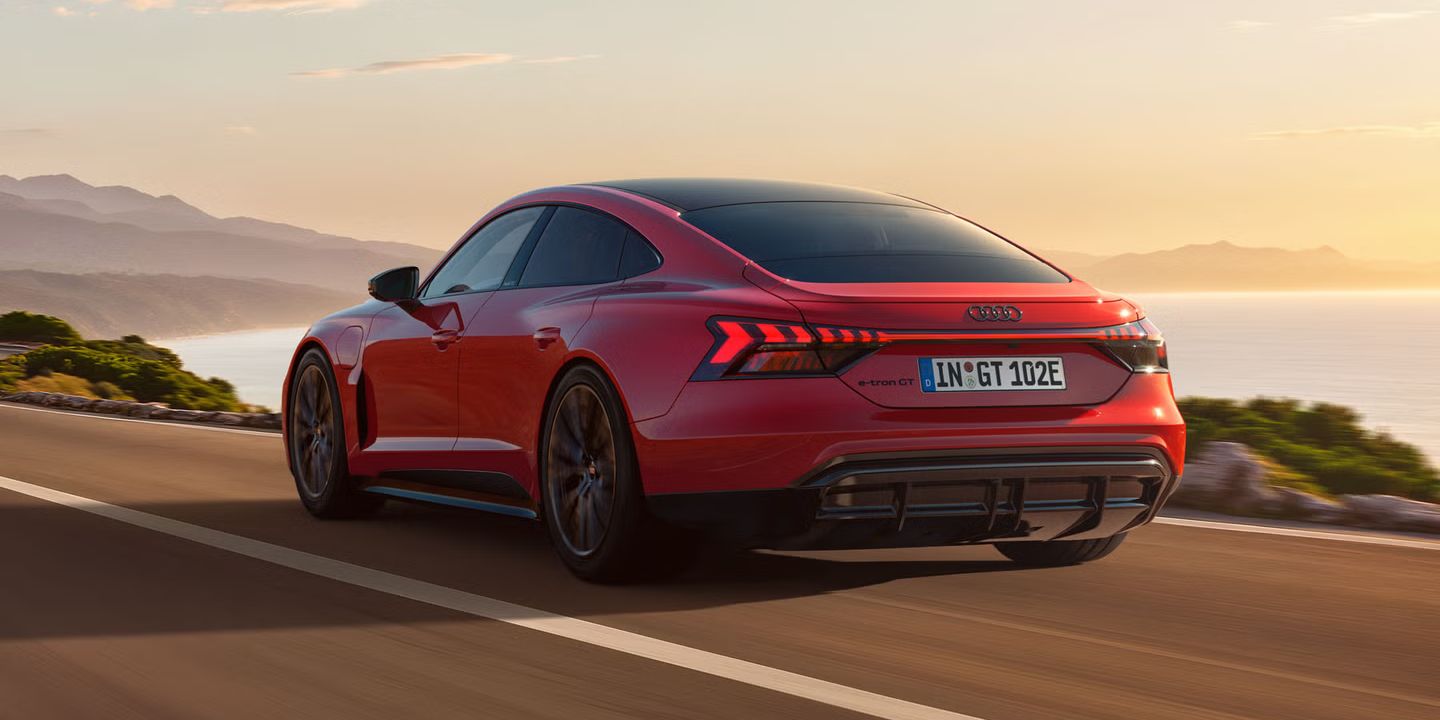 Der e-tron GT quattro auf einer kurvigen Küstenstraße bei Sonnenschein.