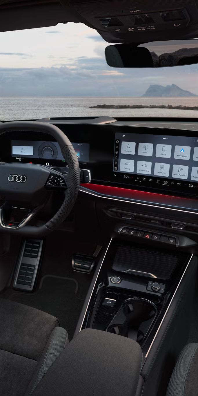 Blick von hinten auf das Cockpit des Q3 SUV mit Lenkrad, Panoramadisplay und rotem Ambiente-Lichtpaket. Durch die Frontscheibe ist das Meer zu sehen.